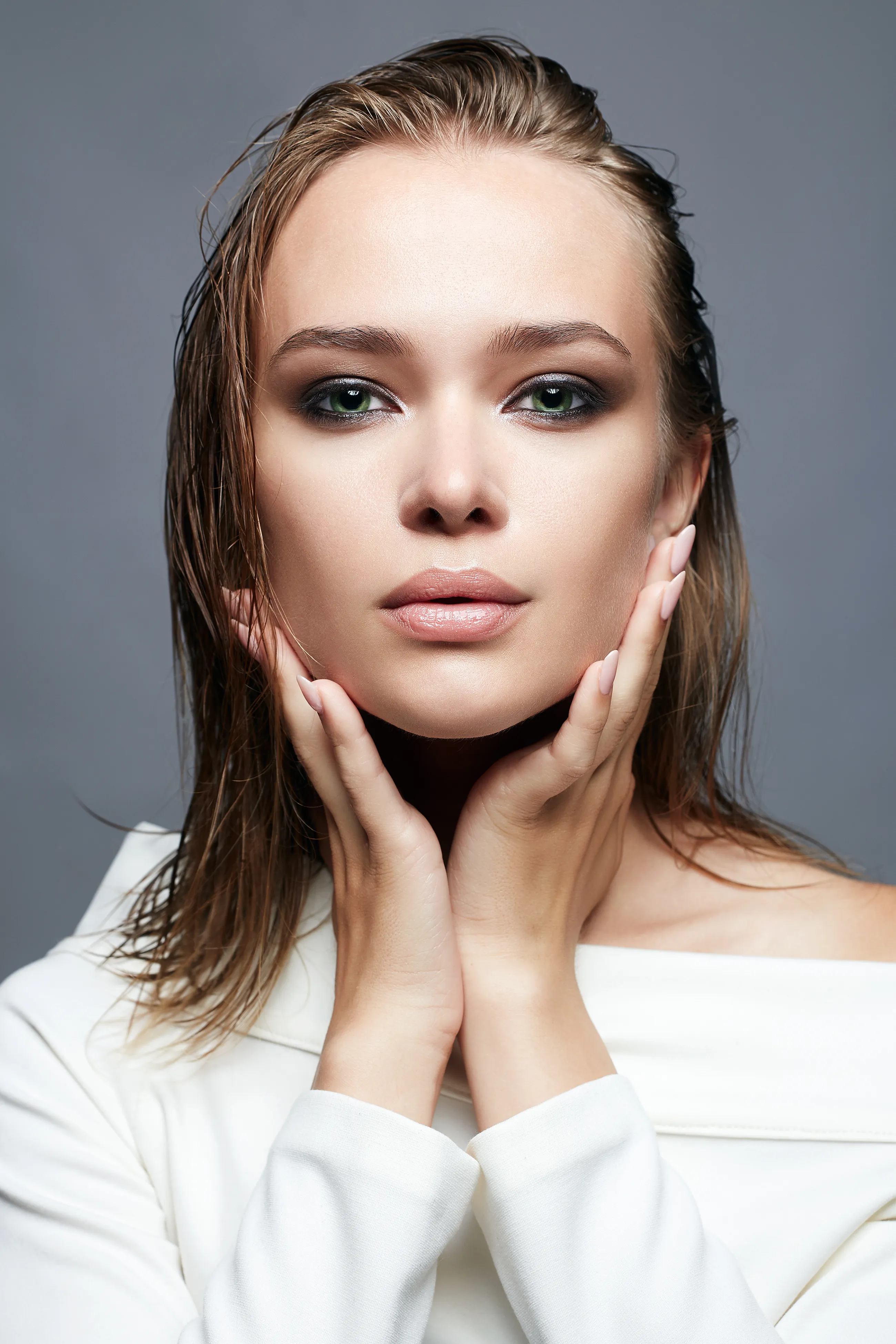 Blondine mit Sleek Look hält Hände an ihr Gesicht