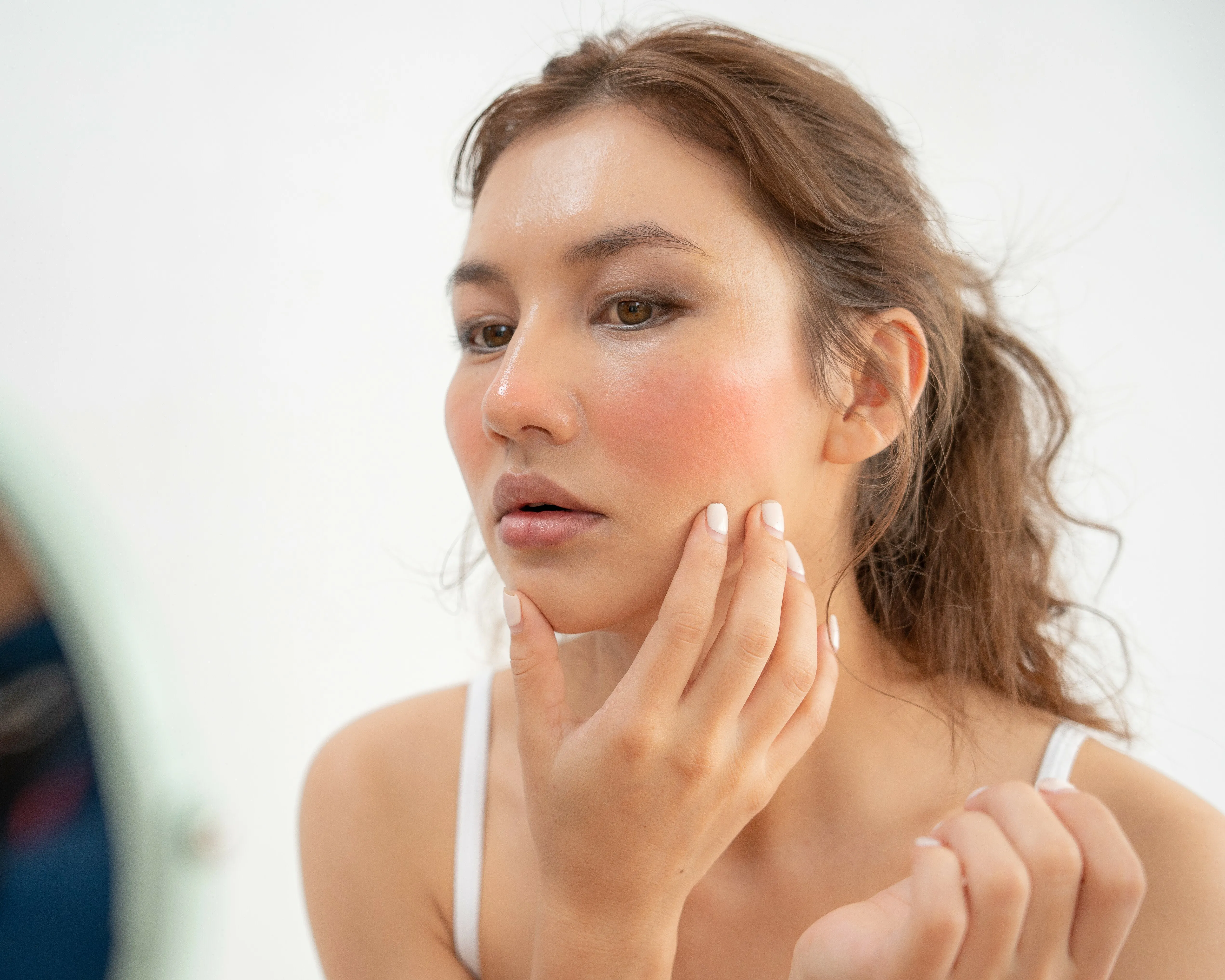 Frau fasst sich ins Gesicht